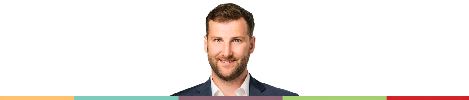 Smiling bearded man in a blue suit jacket looking directly at the camera.
