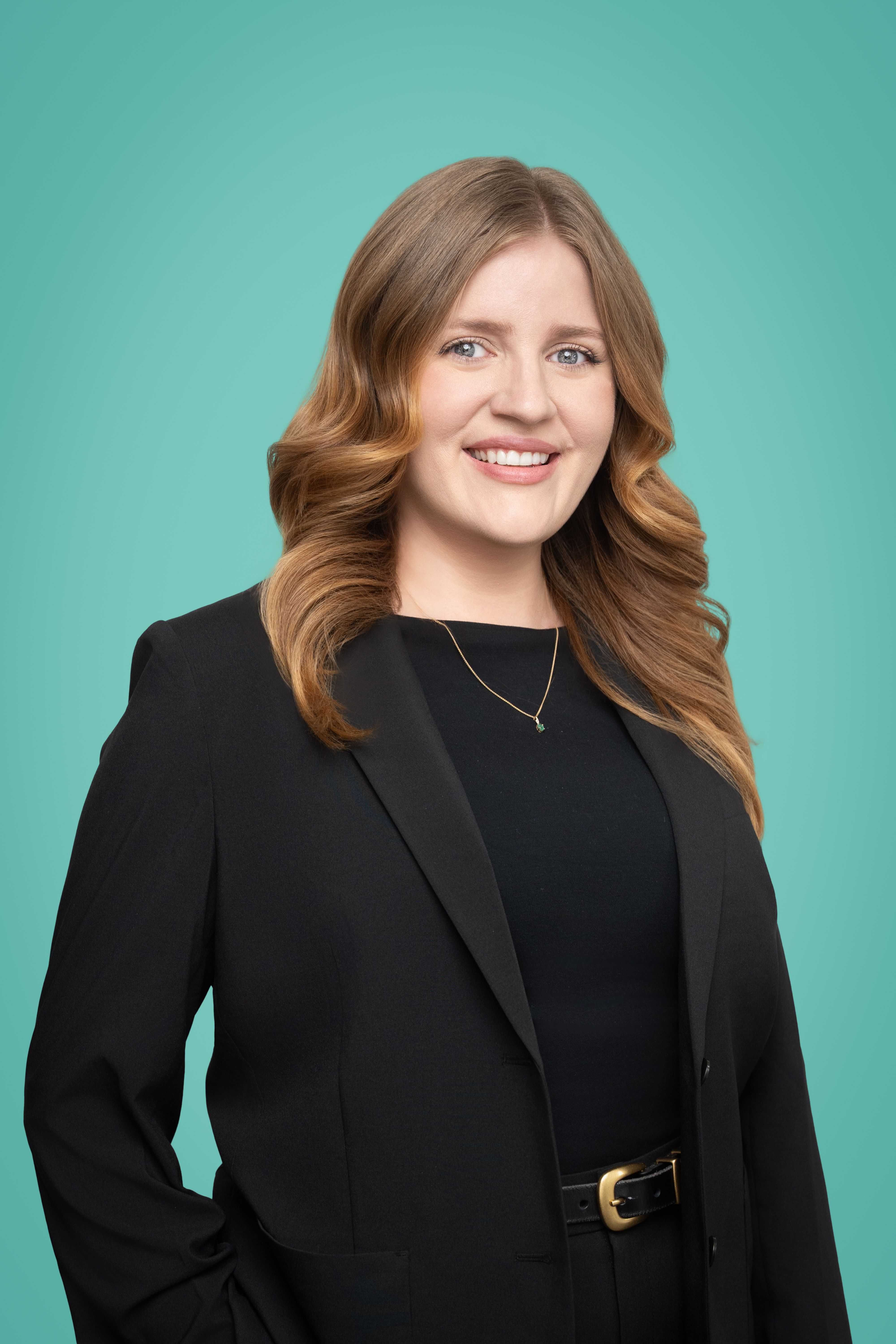 Professional woman with long brown hair smiling against a turquoise background.