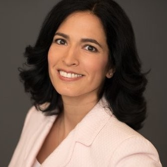 A professional woman with dark hair and a warm smile looking at the camera.