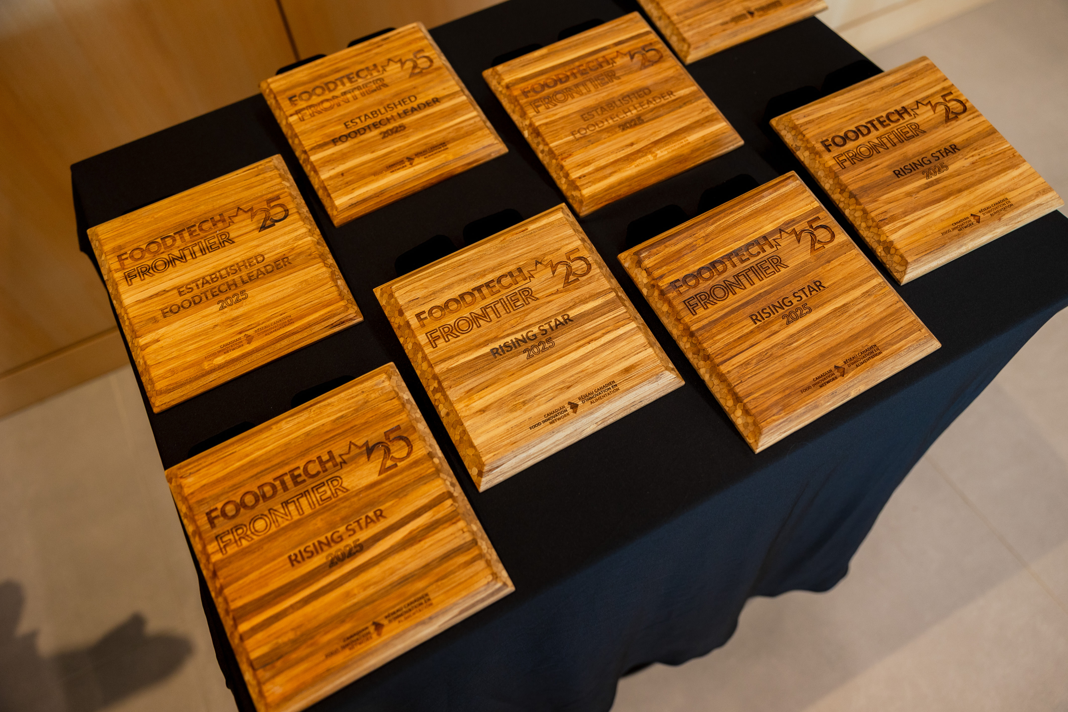 Several wooden awards for FoodTech Frontiers 25 are neatly displayed on a black table.