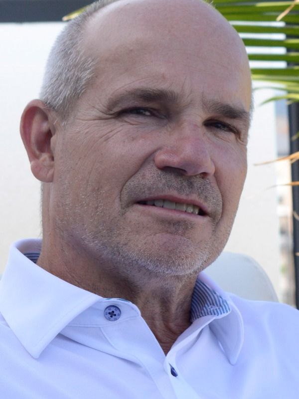 Middle-aged man, bald with gray hair, wearing a white collared shirt.