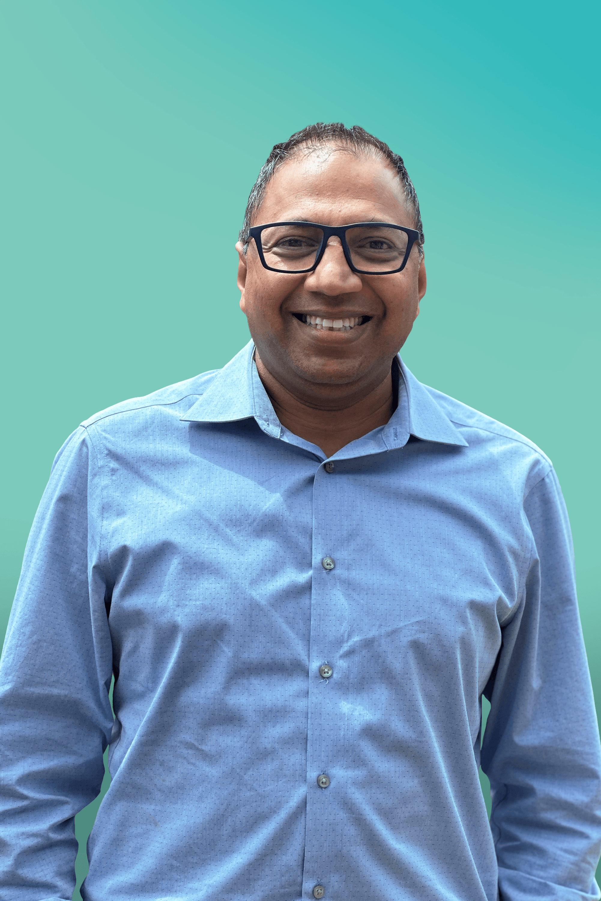A smiling man in glasses and a blue shirt looks directly at the camera.