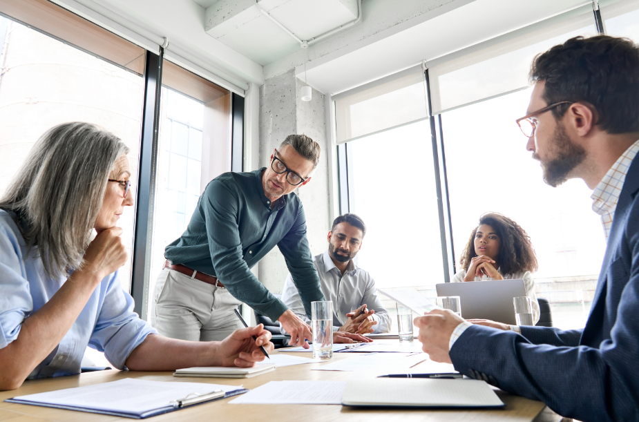Diverse professionals discuss a project during a business meeting in a bright conference room.