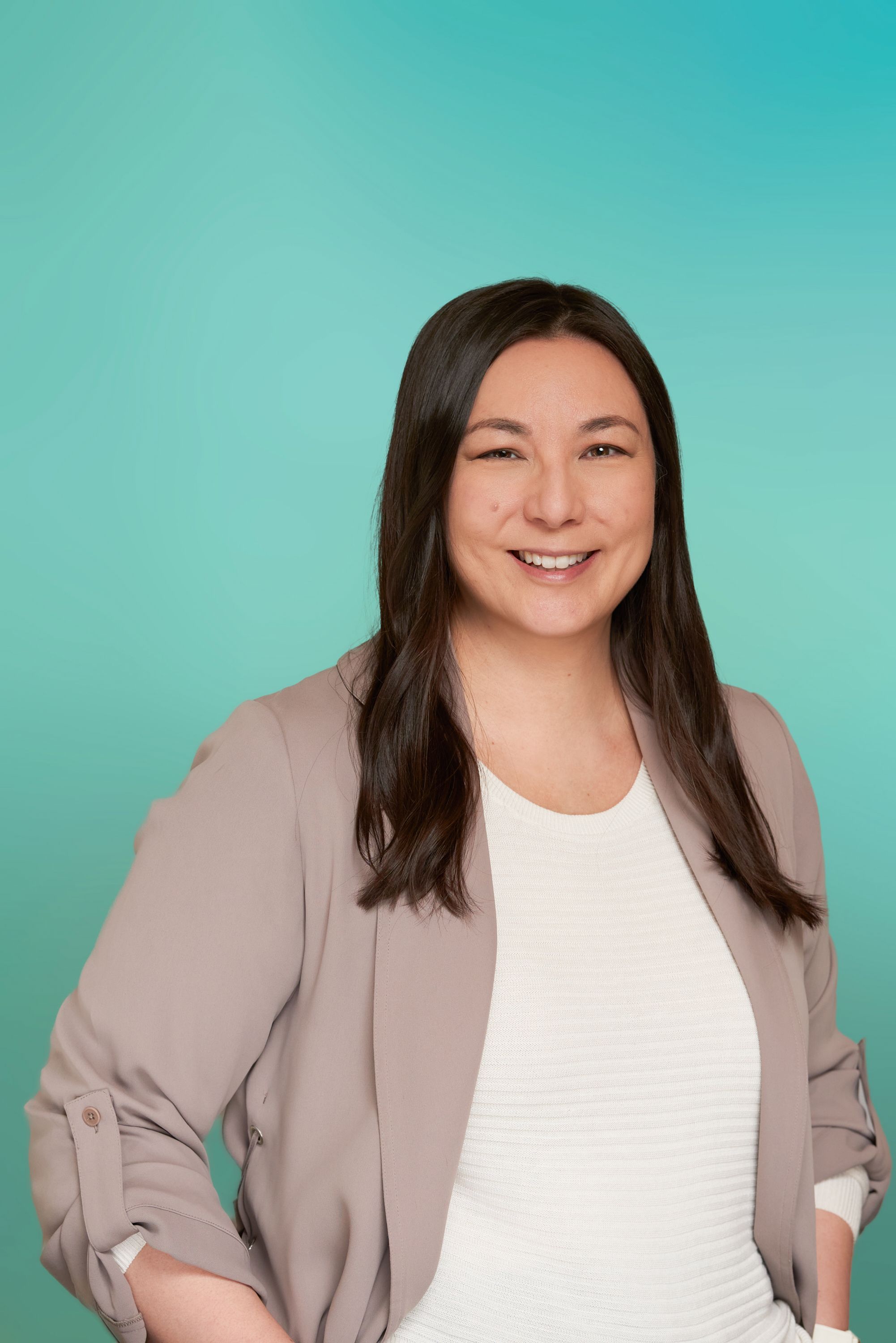 Professional woman with long dark hair smiles confidently against a teal background.