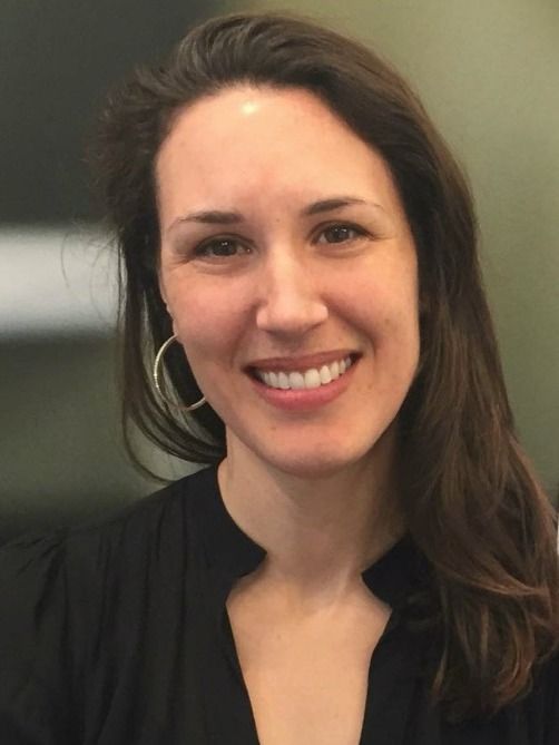 Professional woman with long dark hair smiling directly at the viewer.