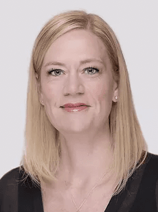 A blonde woman with a neutral expression looks directly at the camera.