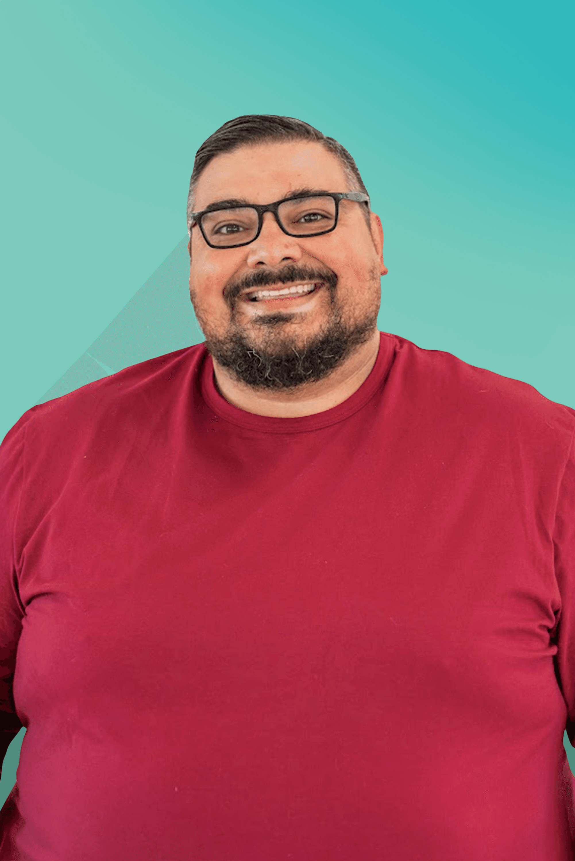 Smiling man with a beard and glasses wearing a red t-shirt against a blue-green background.