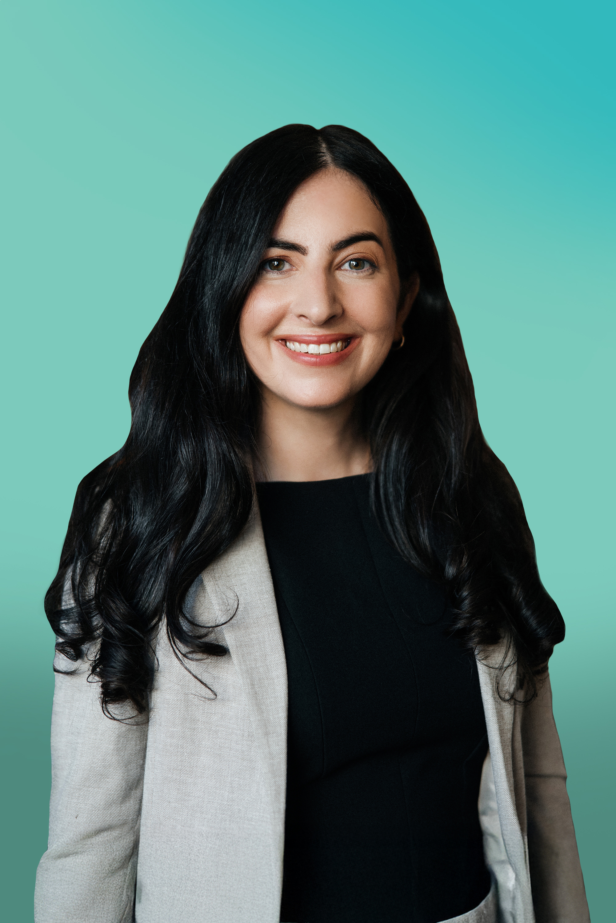 Smiling woman with long dark hair wearing a blazer against a blue-green background.