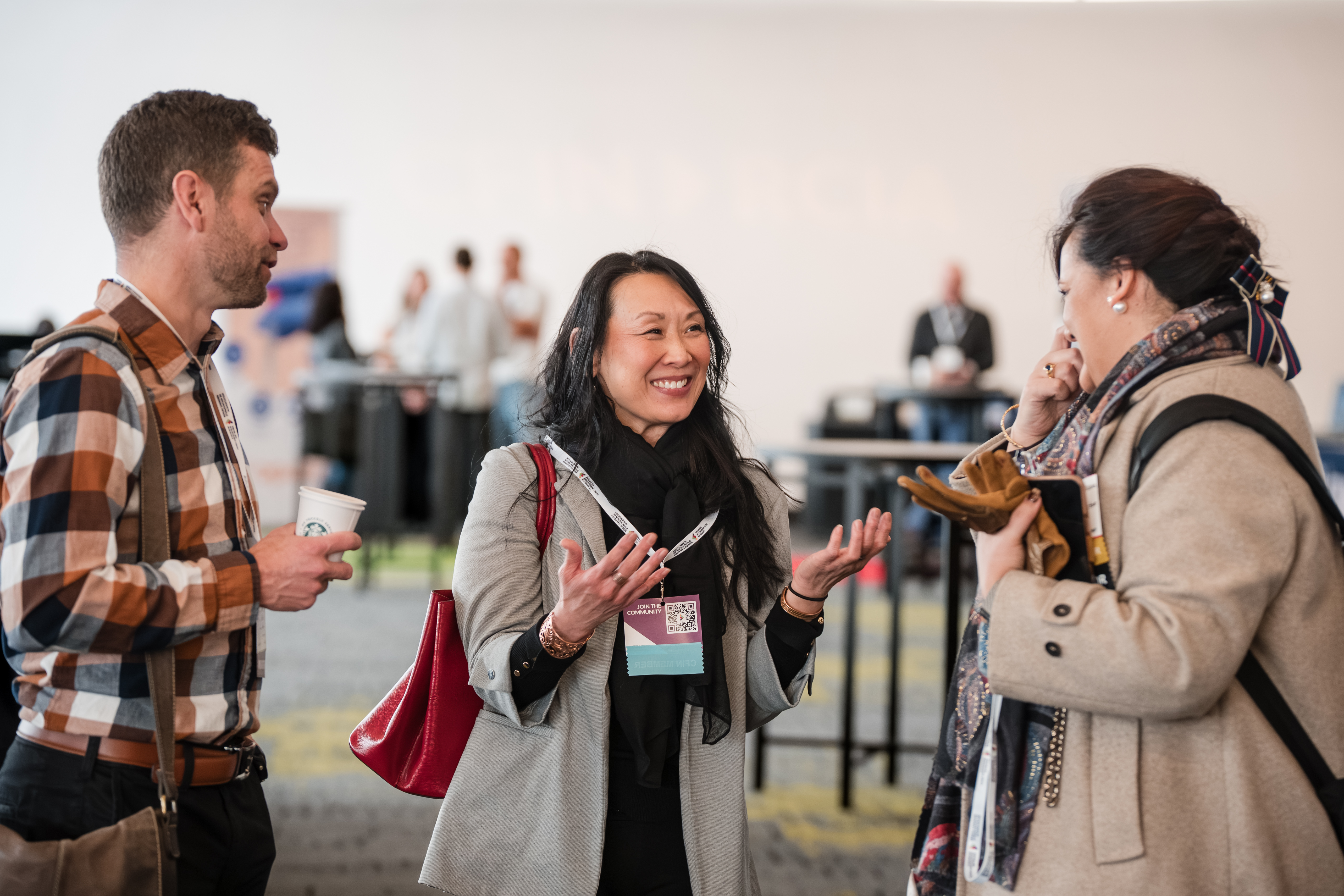 Three professionals actively converse and network at a bright, indoor event.