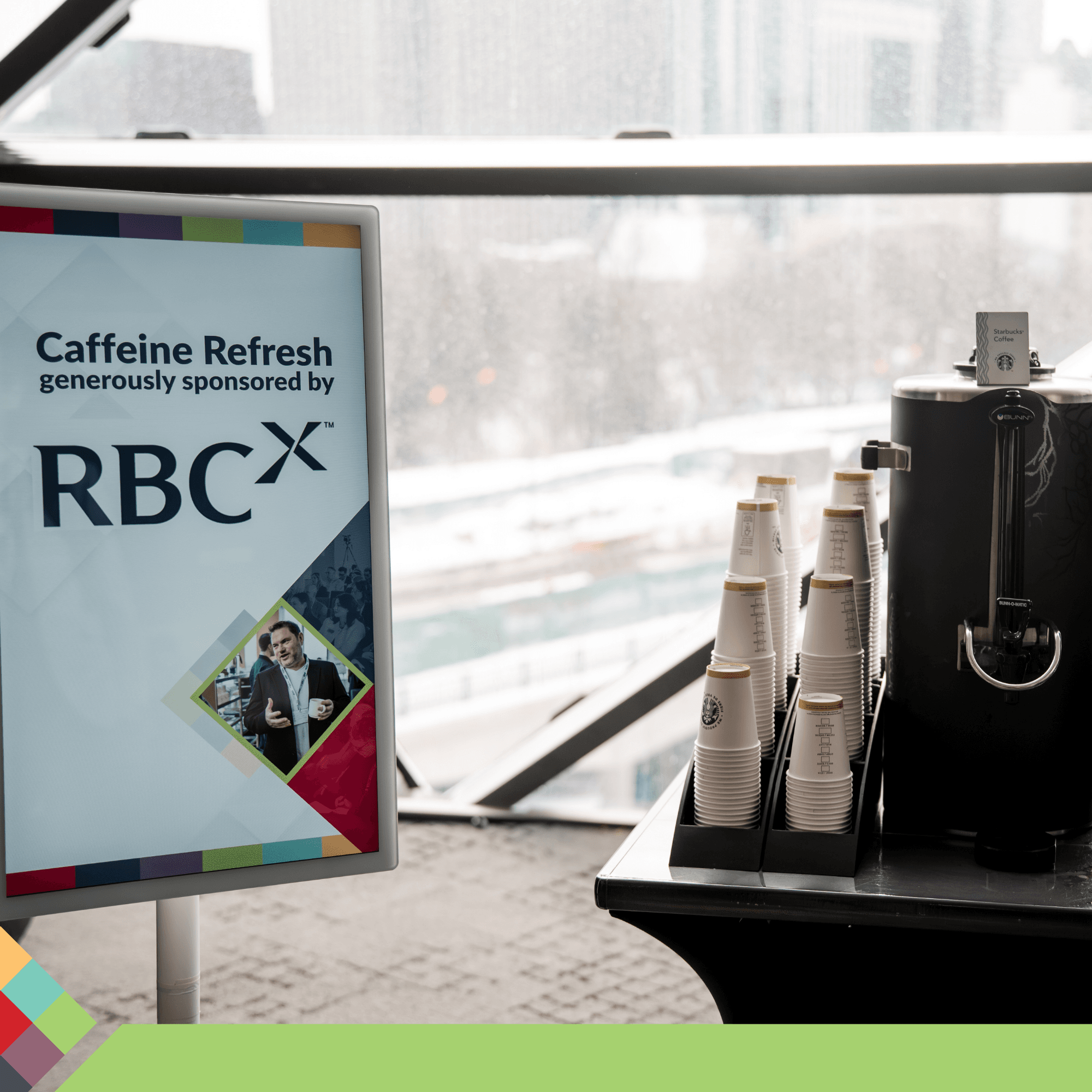Caffeine Refresh sponsored by RBCx sign next to a coffee dispenser and cups.