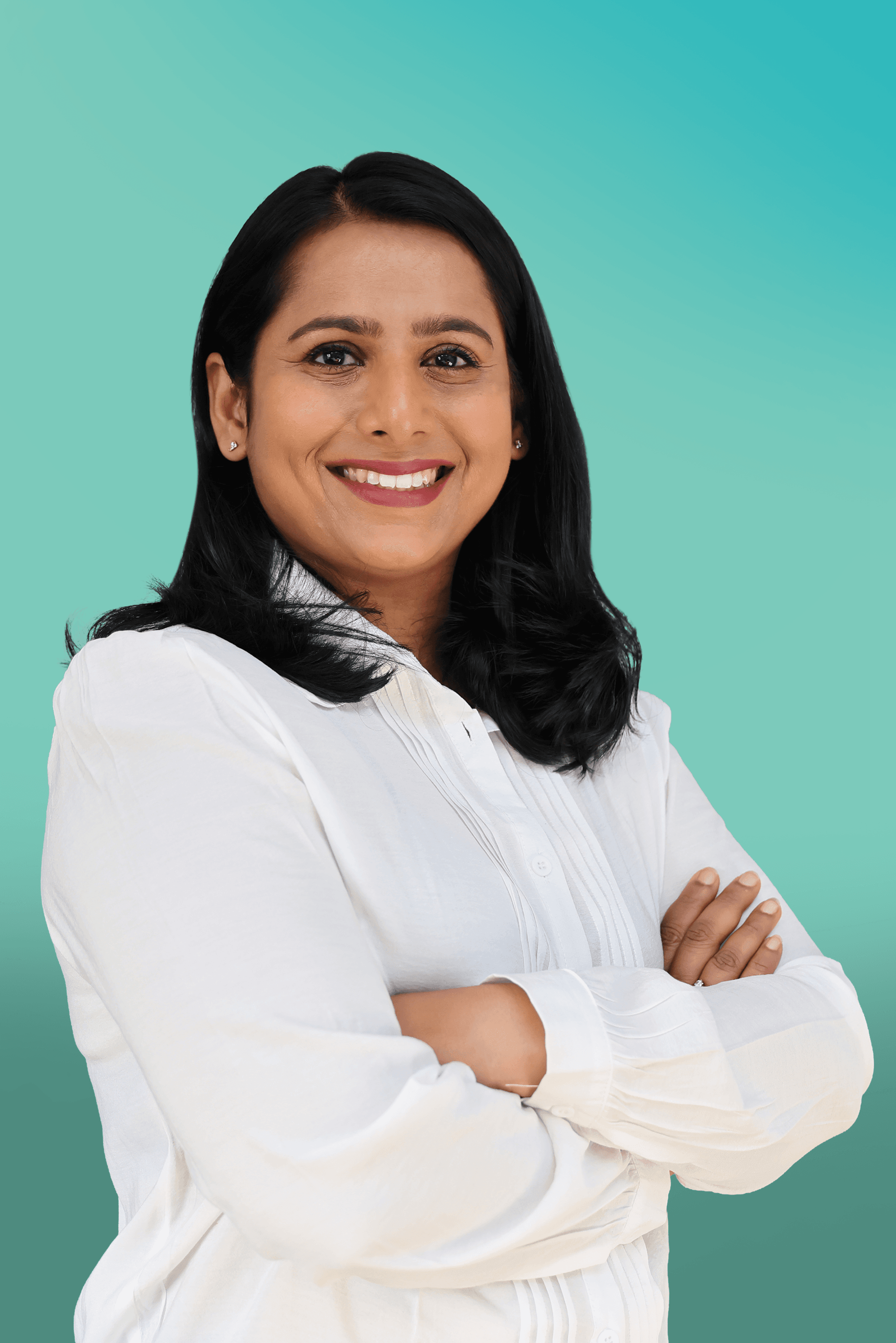 A smiling professional woman with dark hair in a white shirt stands with crossed arms.