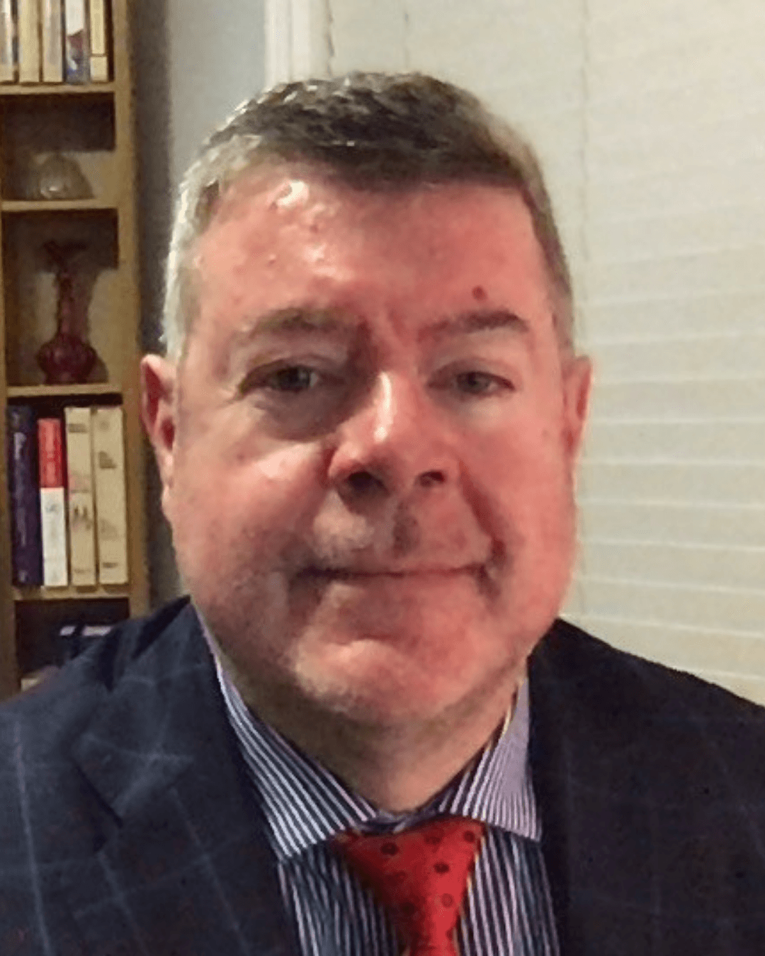 A professional-looking middle-aged man in a suit and red tie looking at the camera.