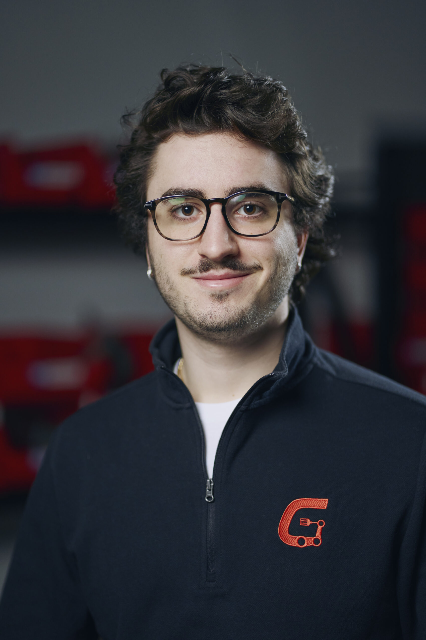 Man with glasses and dark hair wearing a blue sweater with a red 'G' logo.