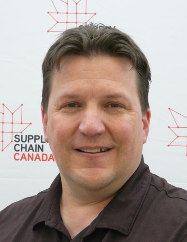 Smiling man in a brown shirt with "Supply Chain Canada" logo in the background.